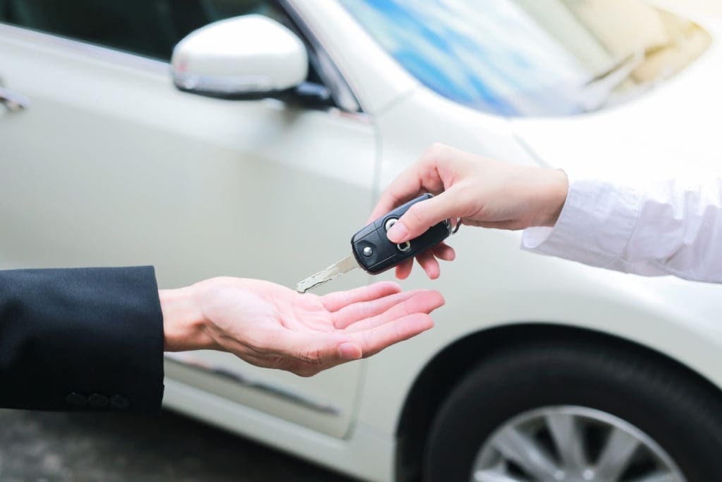 Person handing over car keys to another person in front of a white vehicle cash for cars tx – Don't Trade It In